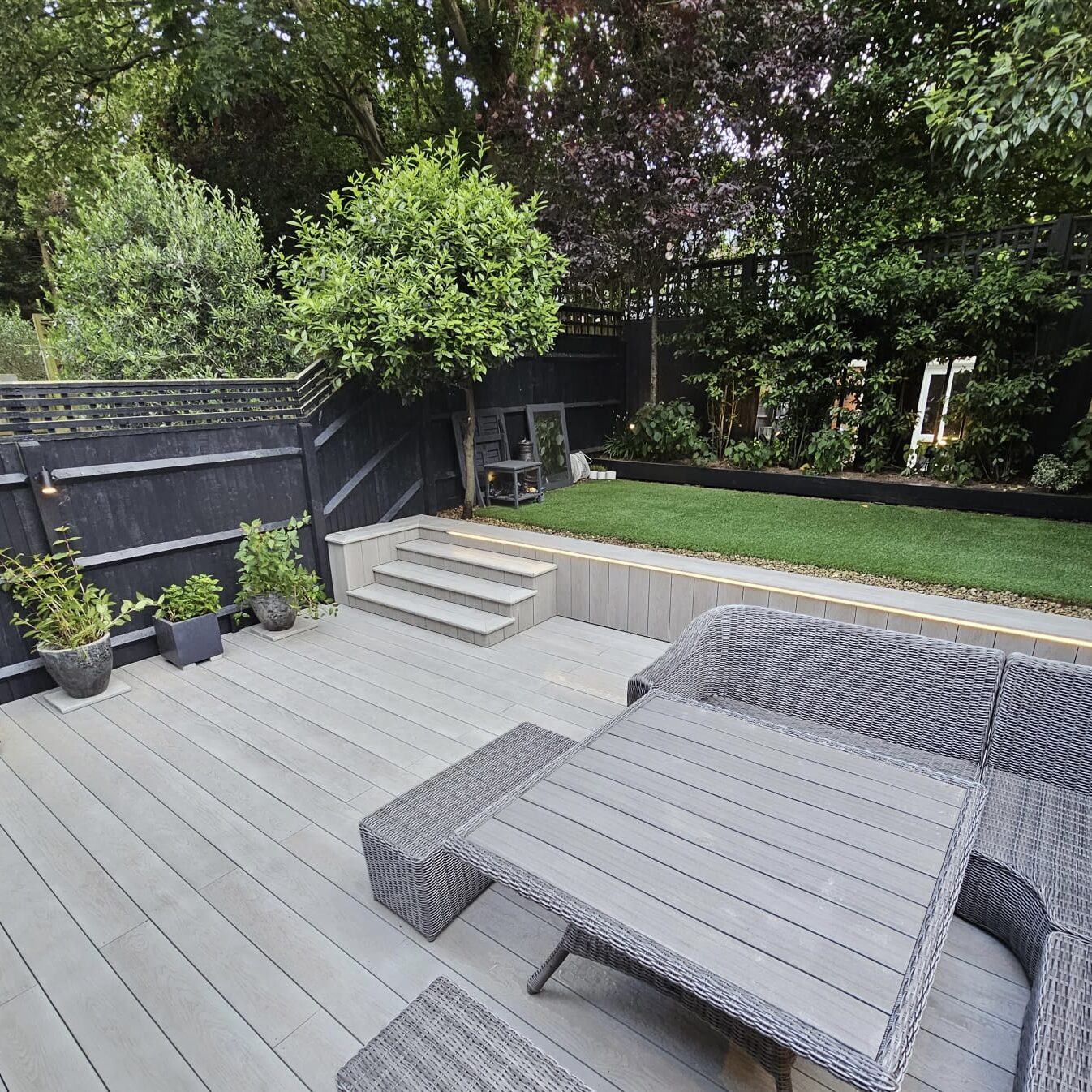 Modern composite decking in Windsor with outdoor seating and lush garden backdrop.